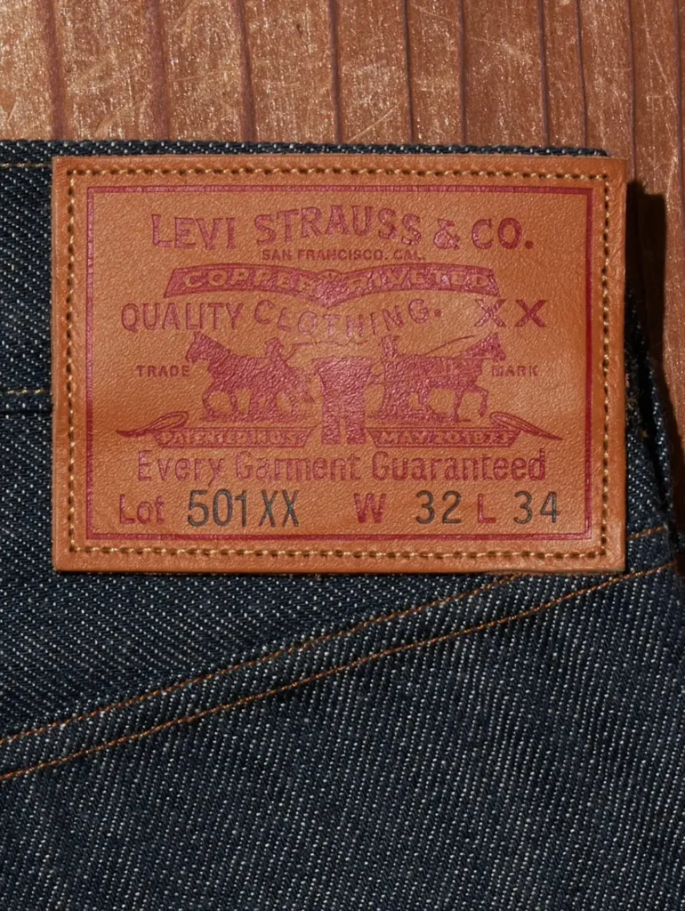 Close-up of the Levi Strauss & Co. leather Two Horse patch embossed with "501 XX" and size markings, stitched onto the waistband of the jean