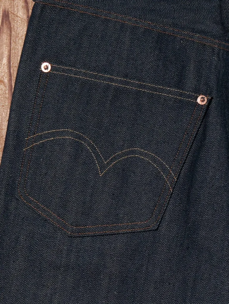Close-up of a rear pocket featuring Levi's iconic arcuate stitching, copper rivets, and rich dark indigo raw selvedge denim texture