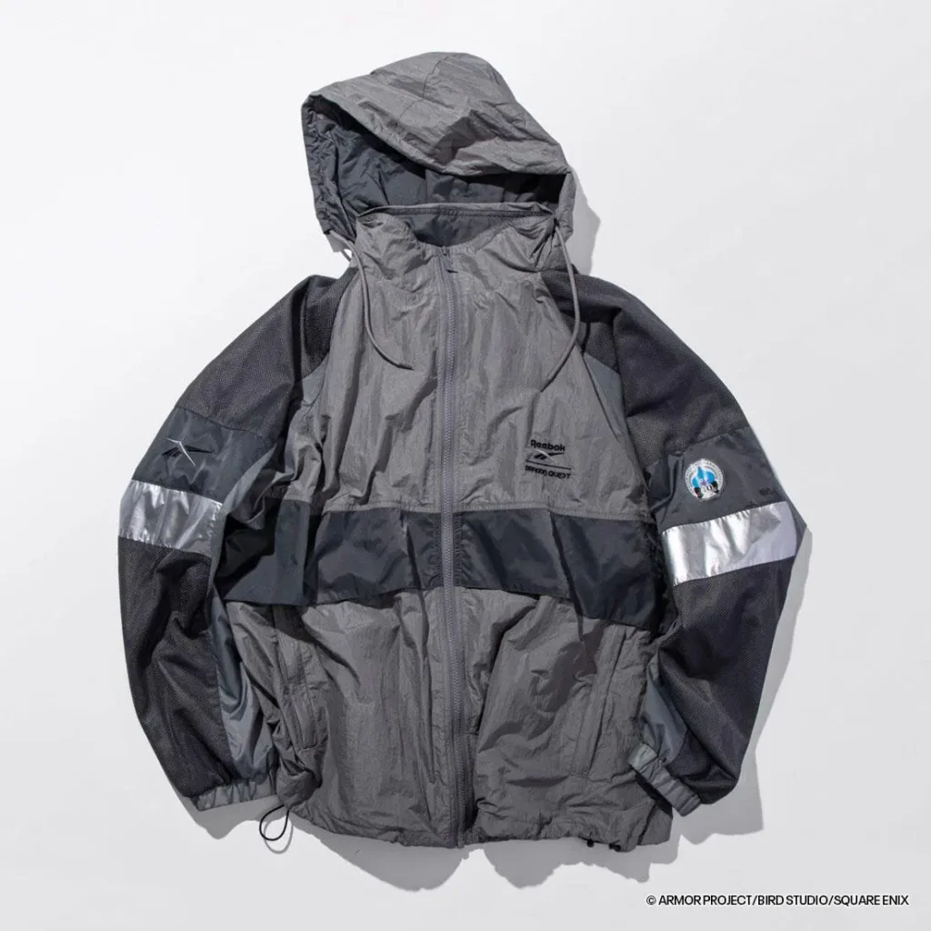 Angled front view of the charcoal gray Dragon Quest jacket with hood raised, reflective sleeve stripes, breathable mesh panels, zip pockets, and technical outdoor-inspired construction