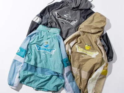 Three lightweight Reebok × Dragon Quest hooded jackets in aqua, charcoal gray, and beige, each featuring breathable mesh panels, reflective accents, and large Dragon Quest graphics on the back