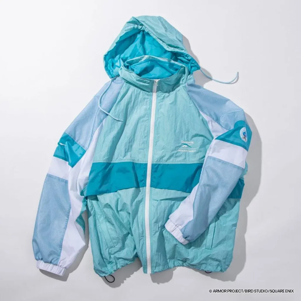 Front view of the aqua Reebok × Dragon Quest hooded jacket with tonal blue color blocking, full-zip closure, mesh sleeves, and collaborative logo embroidery on the chest