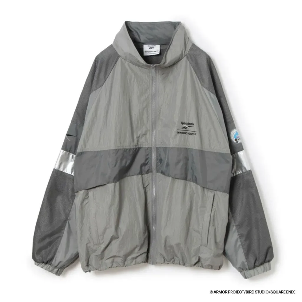 Front view of the charcoal gray Reebok × Dragon Quest hooded jacket featuring layered gray panels, reflective sleeve bands, mesh inserts, and subtle collide chest brand
