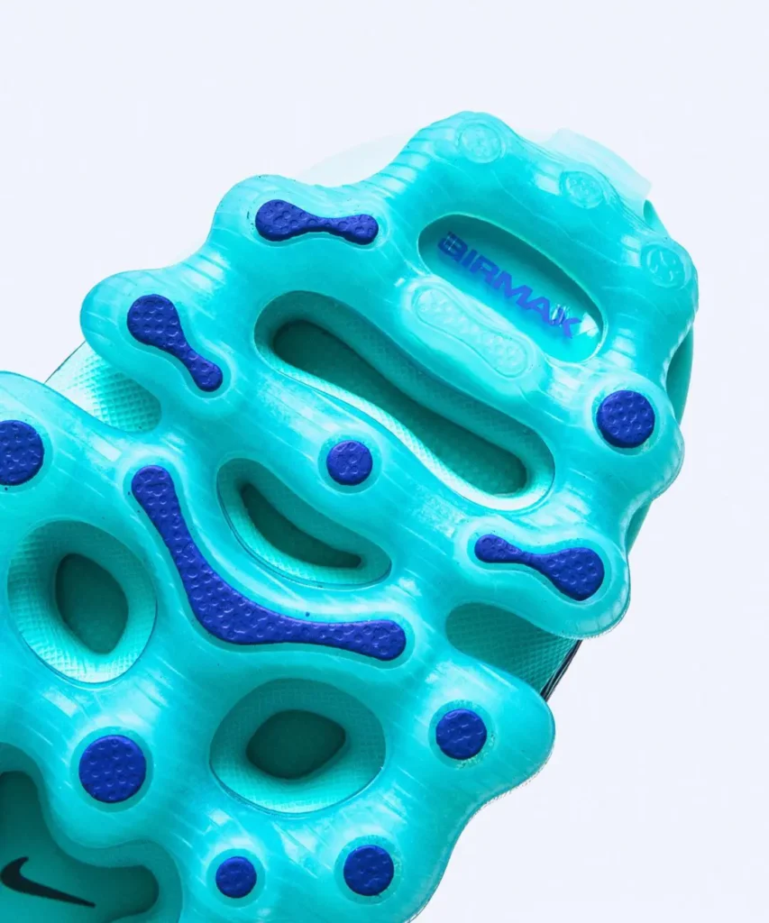 Close-up of the outsole and heel cushioning on the Nike Air Max sneaker, featuring translucent aqua-blue Air pods, dark blue rubber traction inserts, and visible "AIR MAX" branding molded into the heel section