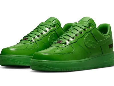 Three-quarter view of bright green Nike Air Force 1 Low shoe pair featuring glossy leather uppers, tonal midsoles, ostrich-textured Swooshes, metallic lace dubraes, and black "1100N" heel brand