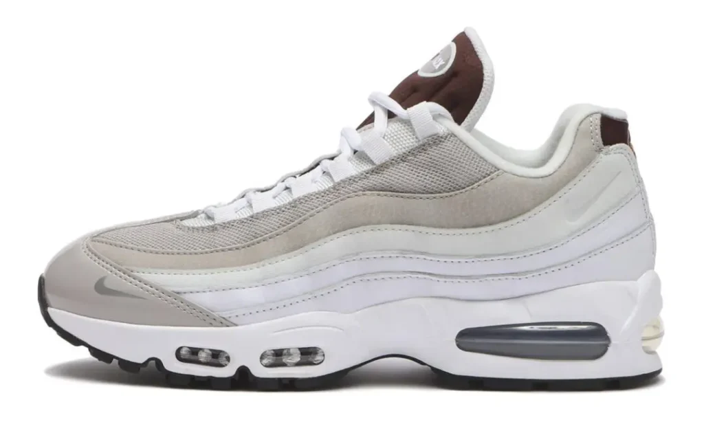 Lateral side profile of the Nike Air Max 95 displaying gradient-inspired layered panels in white and light grey, breathable mesh upper, reflective toe Swoosh, brown tongue, and exposed Air Max cushioning throughout the white mid