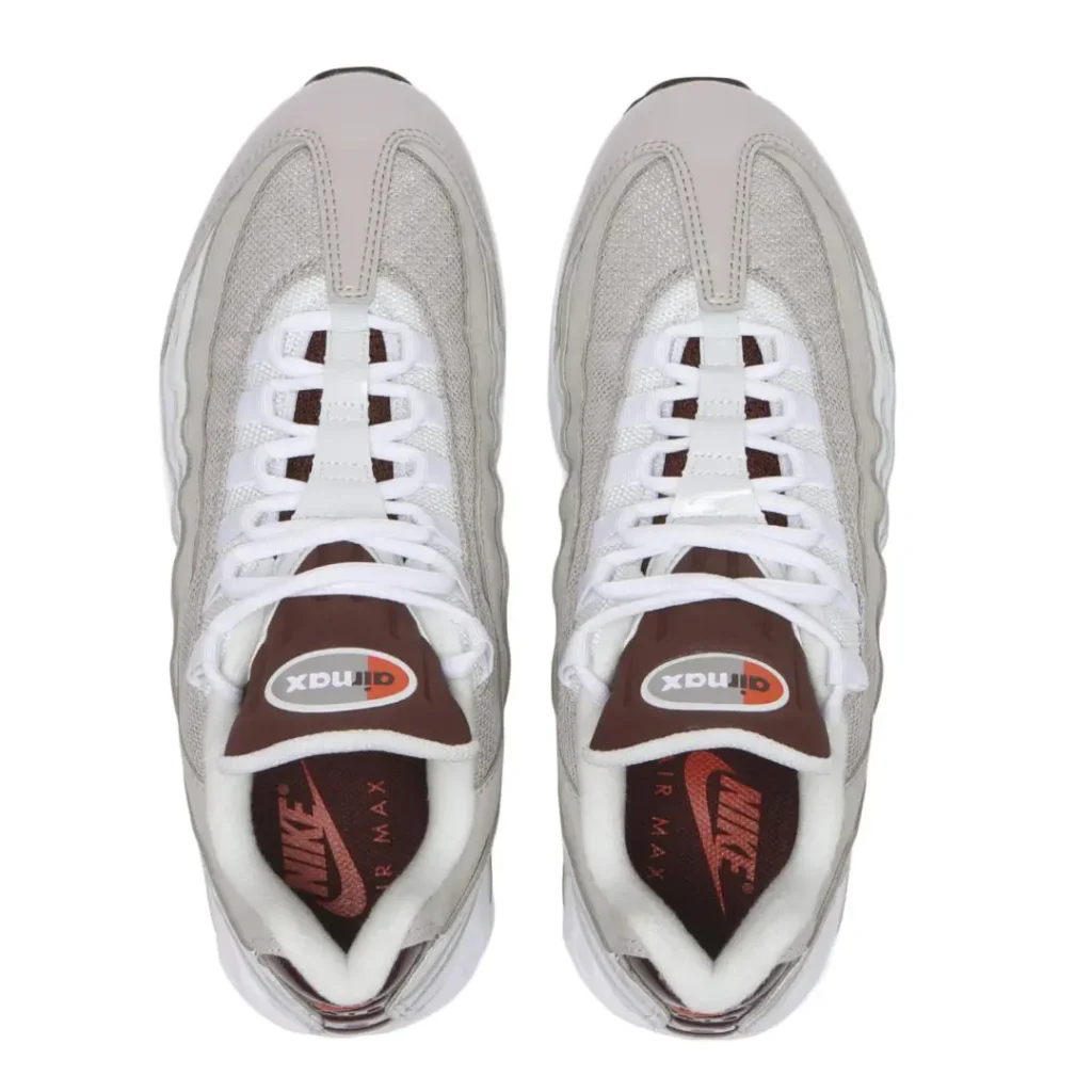 Top-down view of the Nike Air Max 95 showing white laces over a light grey mesh upper, padded brown tongues with vintage Air Max logos, plush white lining, and branded brown insoles with metallic bronze Nike Air graphic