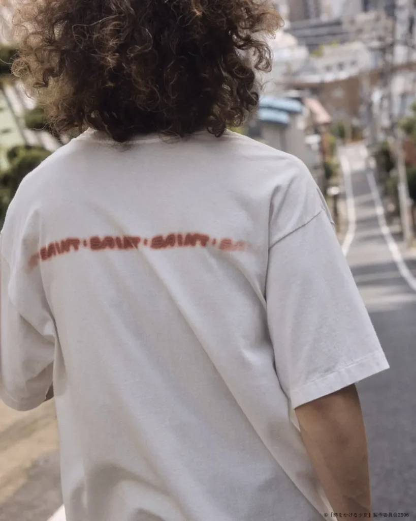 Close-up rear view of the oversized white graphic T-shirt highlighting the soft-focus red text print spanning the upper back above the relaxed drape