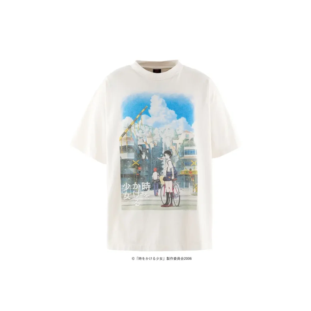 Front product image of an oversized white T-shirt featuring a large anime-inspired illustration of a Japanese city street with vivid blue skies, clouds, trains, and character
