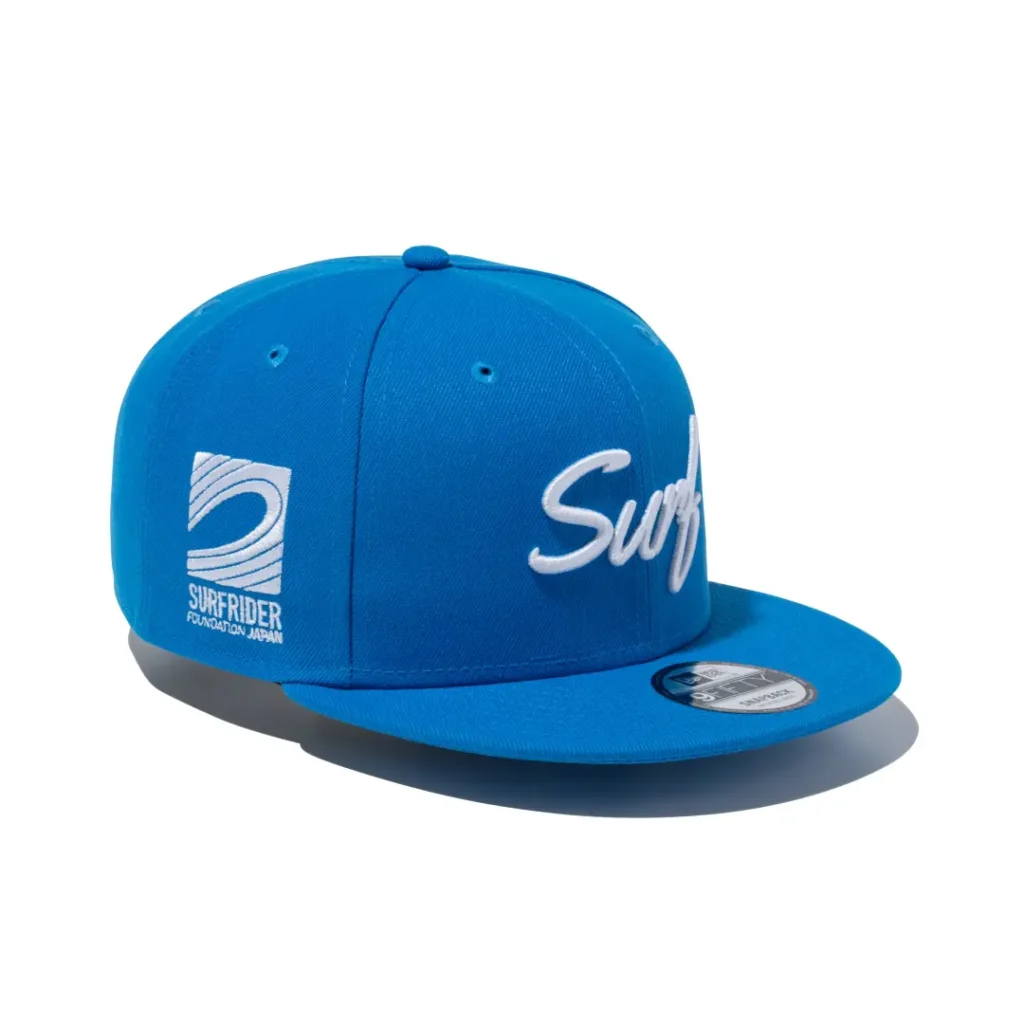 Bright blue flat brim snapback featuring white script "Surf" embroidery across the front and Surf Rider Foundation Japan logo on the side
