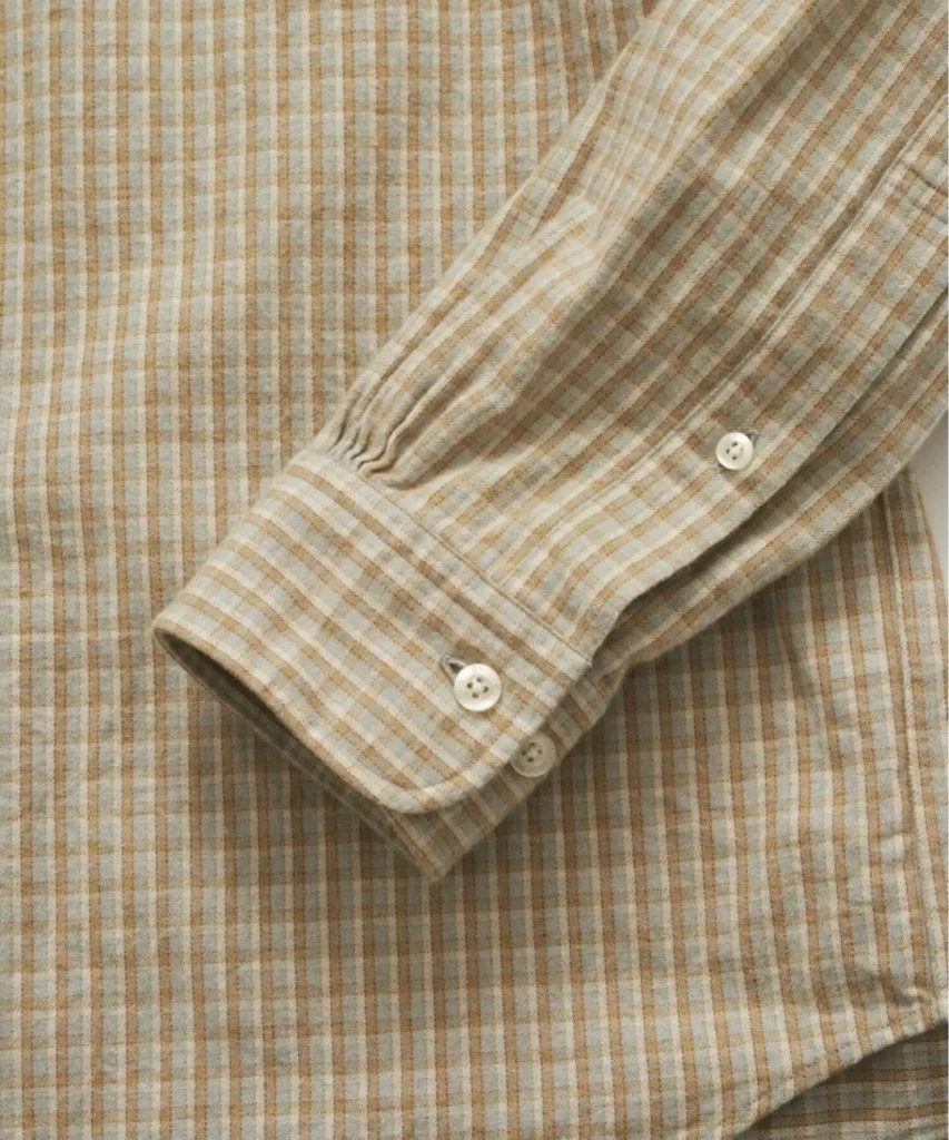 Close-up of the beige Brooks Brothers British Check Shirt highlighting the brushed flannel texture, tan-and-cream British check pattern, gathered sleeve, adjustable button cuff, and soft woven finish that defines the fabric's casual character