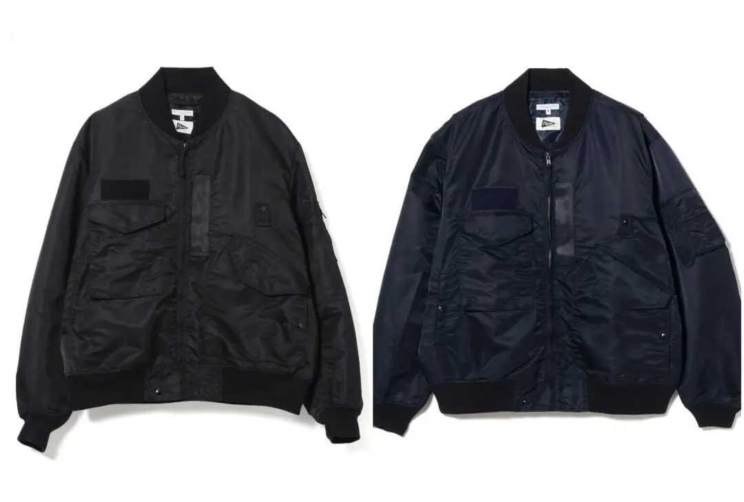 Black and navy nylon bomber jackets displayed side by side, featuring oversized cargo pockets, ribbed collars, zip-front closures, and military-inspired utility detailing from the Pilgrim x Engineered Garments collaboration.