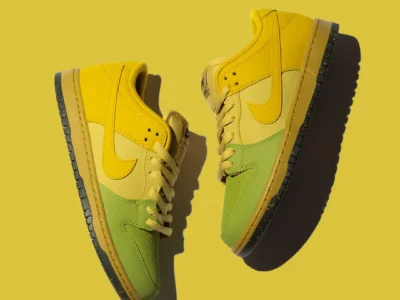 Two Nike SB Dunk Low Pro shoe in yellow, cream, and sage green leather float against a solid yellow background, highlighting the gradient-inspired color blocking and black speckled outsole