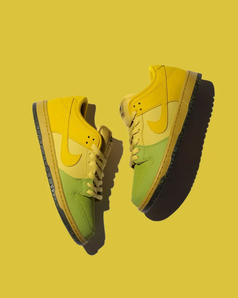 Two Nike SB Dunk Low Pro shoe in yellow, cream, and sage green leather float against a solid yellow background, highlighting the gradient-inspired color blocking and black speckled outsole