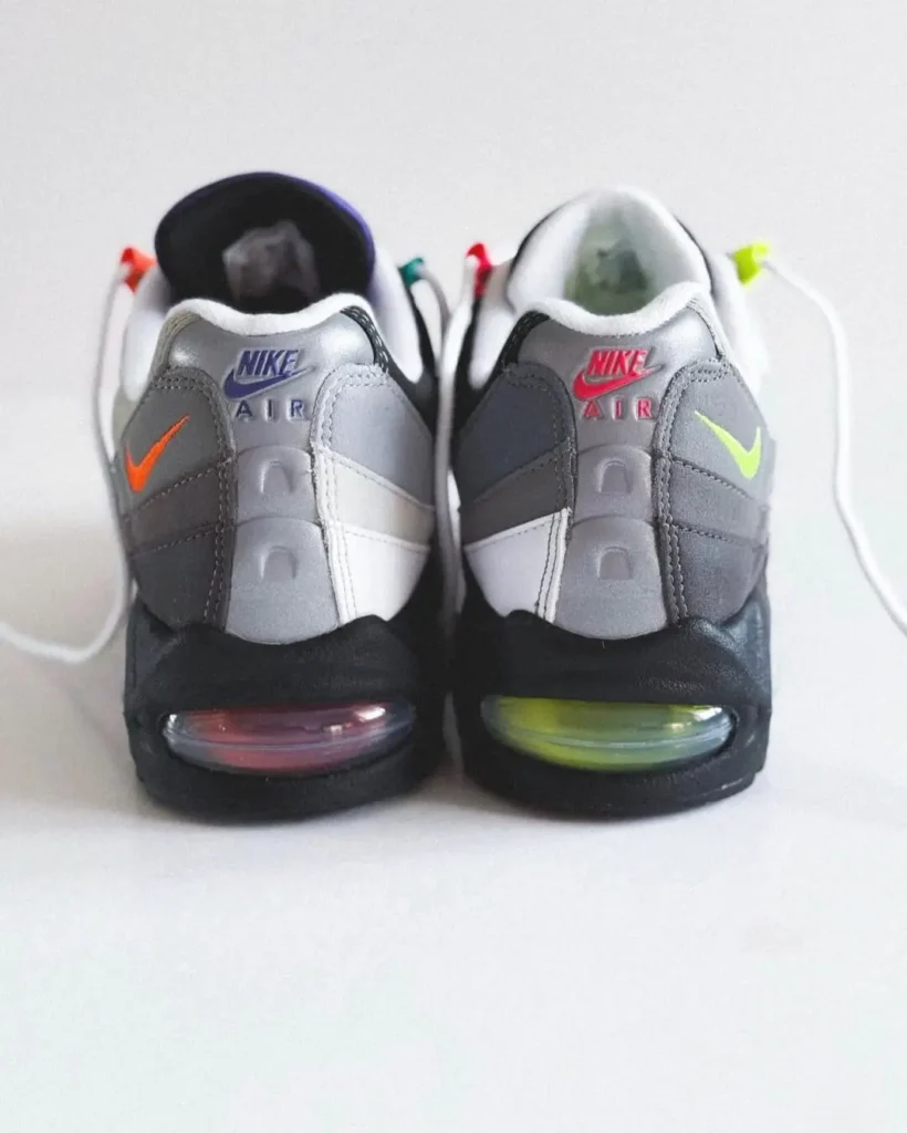Heel view of the mismatched Nike Air Max 95 highlighting contrasting purple and pink Nike Air embroidery, neon mini Swooshes, and differently tinted Air unit
