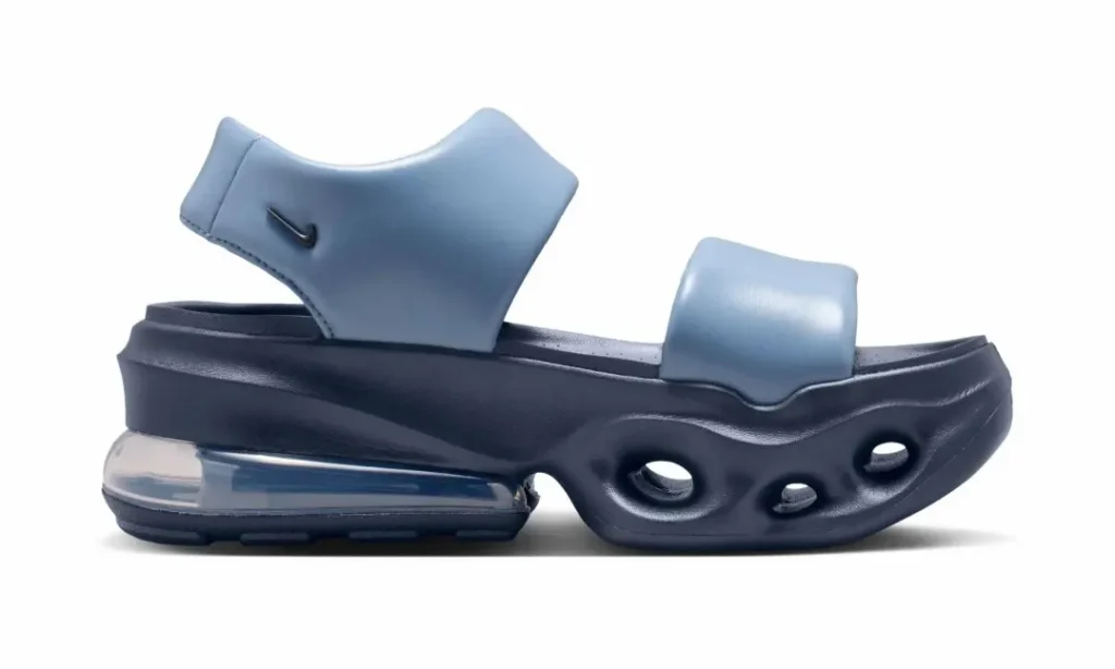 Medial side profile of the Nike Air Max platform sandal showcasing the oversized sculpted sole and exposed Air Max heel unit. The light blue padded upper contrasts with the dark navy foam platform, while rounded cutout details along the midsole reinforce the sandal's modern, show-inspired aesthetic