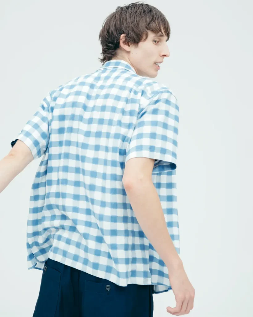 Front view of a model wearing a navy Human Made heart-logo T-shirt beneath an open blue gingham overshirt