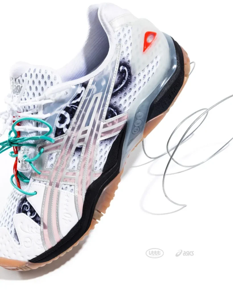 Close-up side profile of the white ASICS x Lttt shoe highlighting the translucent ASICS logo cage, black ornamental graphics, perforated mesh upper, and red heel window detail