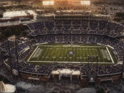 Vintage-style aerial view of a packed football stadium at sunset with warm tones, soft blur, and 1980s film grain