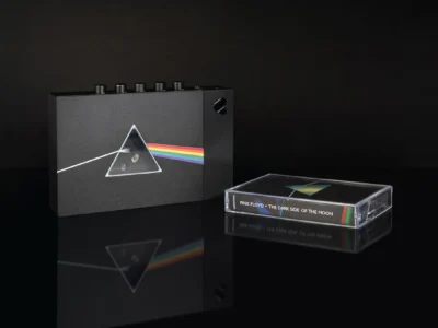 Black We Are Rewind cassette player featuring Pink Floyd's The Dark Side of the Moon prism artwork beside a matching cassette tape on a glossy black reflective surface