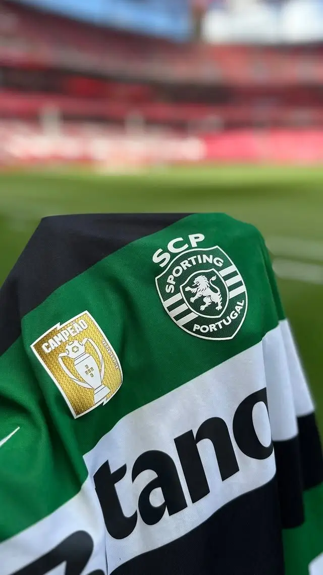 Close-up of Sporting CP's 2026–27 home jersey featuring the club crest, Liga Portugal champions badge, and green-and-white hoops inside the stadium.