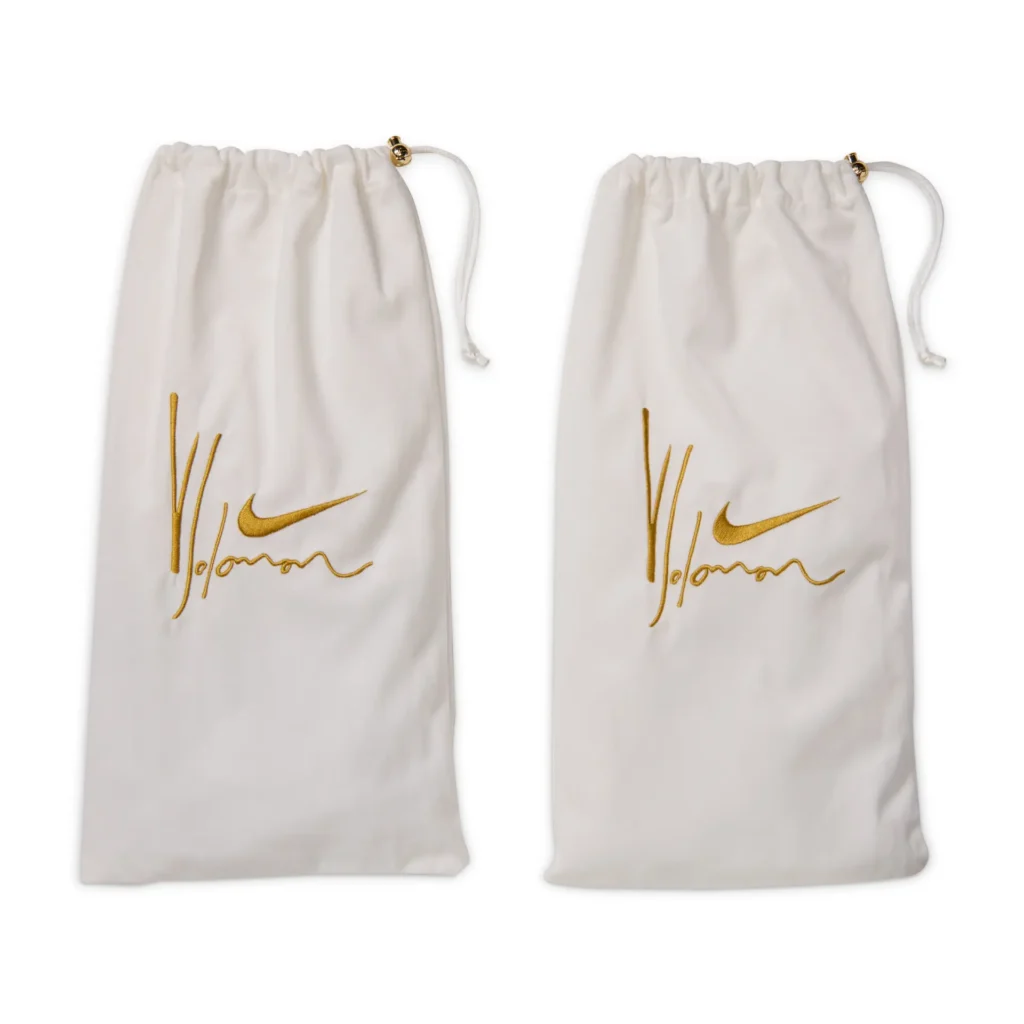 Pair of white drawstring dust bags embroidered with gold Nike Swoosh and Yoon signature branding, included with the special-edition Nike Air Force 1 release