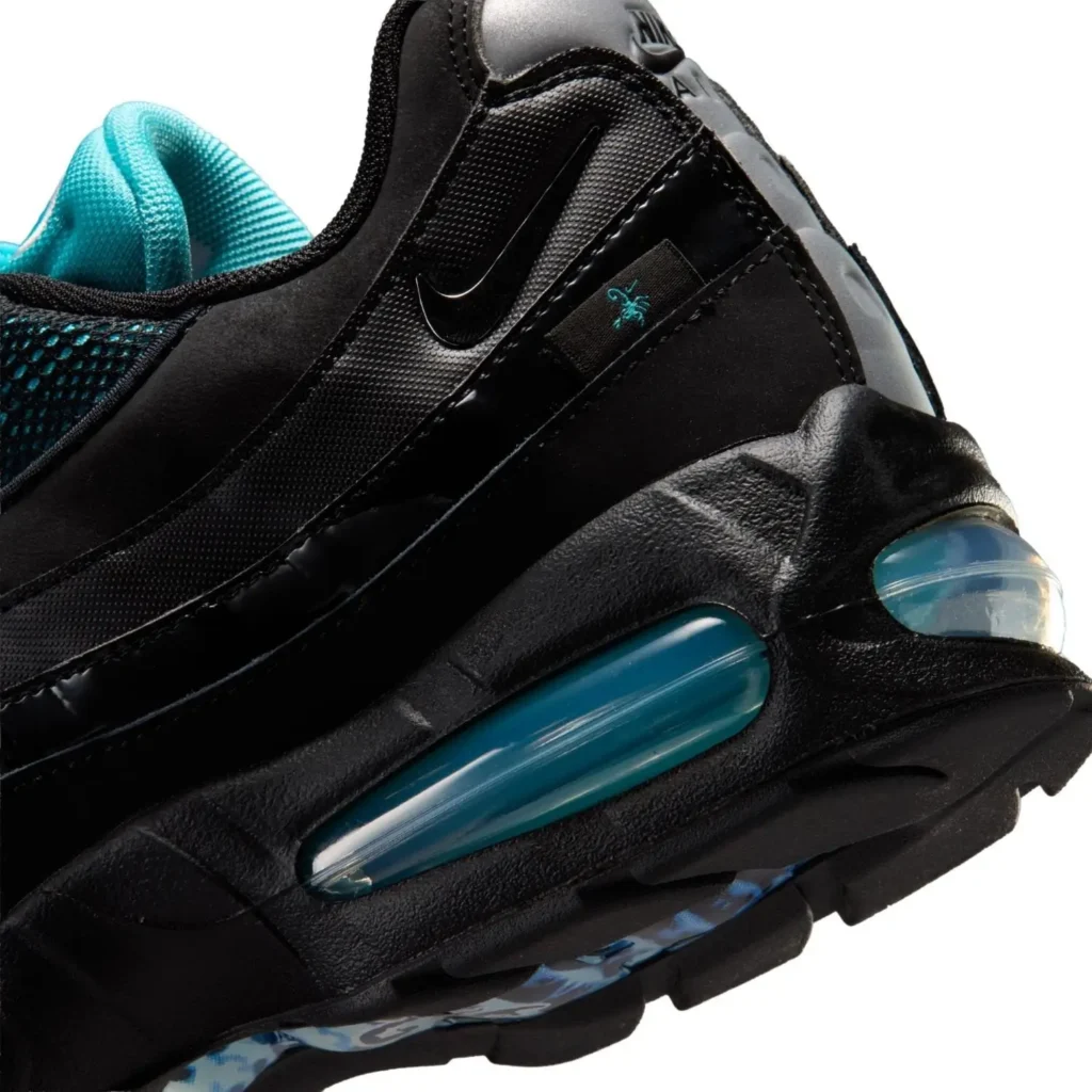 Close-up side detail of the Nike Air Max 95 in black and aqua, highlighting the glossy layered mudguard, textured mesh upper, mini Swoosh, embroidered spider graphic, and translucent blue Air Max cushioning unit