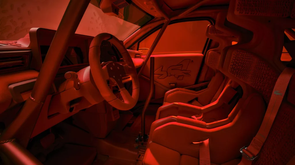 Wide view of the Alpine A290 Rallye cockpit finished entirely in red, showcasing racing bucket seats, roll cage, rally steering wheel, and custom Lacoste crocodile branding on the door panel