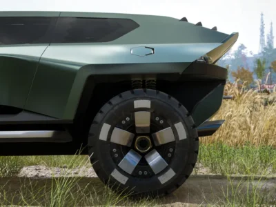 Side profile close-up of the Aston Martin pickup concept, highlighting the sculpted matte green bodywork, sharply flared rear wheel arch, oversized off-road tire with geometric alloy wheel, exposed rear suspension springs, angular rear overhang, and flush hexagonal fuel cap against a grassy outdoor landscape