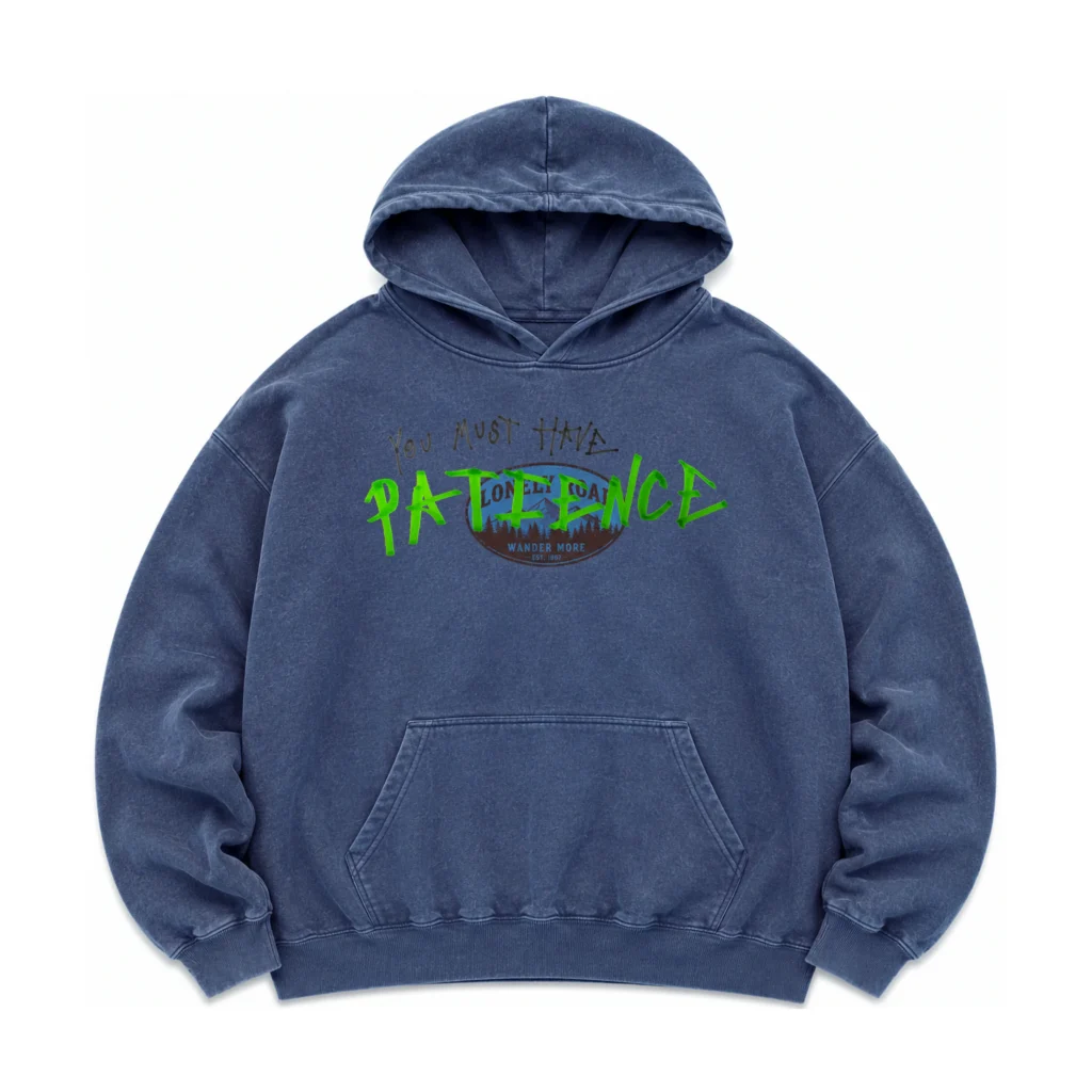 Vintage washed blue pullover hoodie featuring a faded outdoor-inspired badge graphic beneath a handwritten "You Must Have PATIENCE" design in black and vivid green