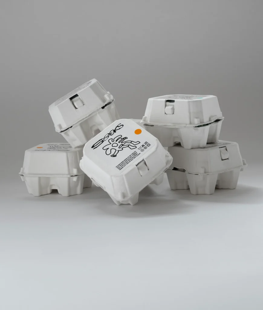 Stack of white Crumpler branded molded fiber packaging boxes arranged against a neutral gray background, showcasing the brand's custom retail package