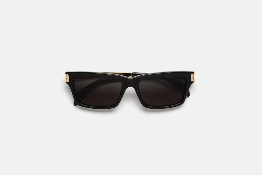 Black rectangular sunglasses with dark smoke lenses, sculpted glossy acetate frame, and gold toned temple accents shown in a front-facing studio view
