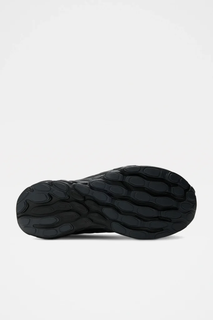 Bottom view of the New Balance running shoe displaying the full black rubber outsole with an organic oval-shaped traction pattern designed for grip and durable against a white background