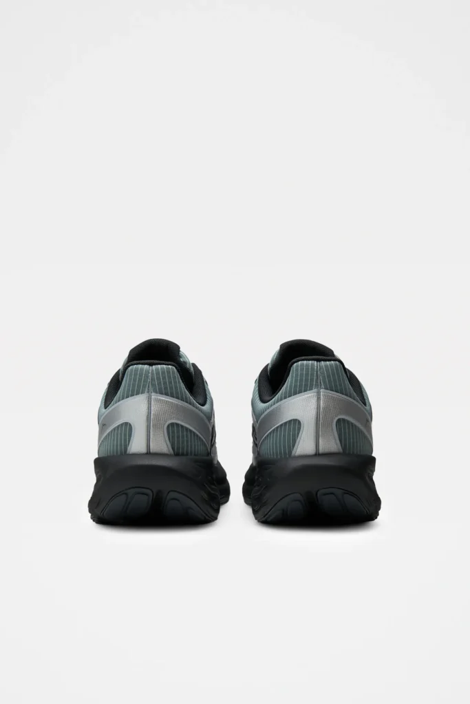 Rear view of the pair showing striped gray-green heel panels, metallic silver heel counters, padded black collars, and sculpted black Fresh Foam X midsoles on a white studio backdrop