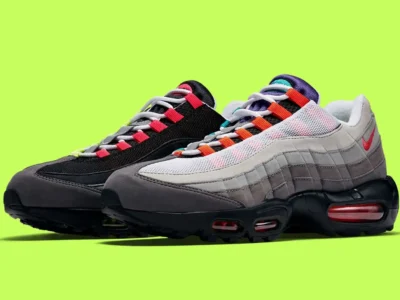 Promotional image of the mismatched Nike Air Max 95 against a bright lime-green background, emphasizing inverted black-and-white uppers, colorful lace loops, grey overlays, and red-tinted Air Max cushion