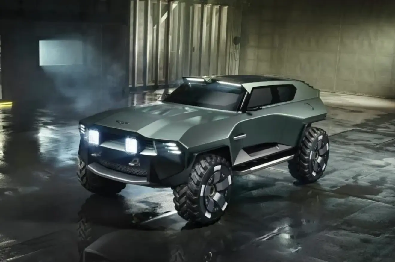 Three-quarter front view of the Aston Martin Dreadnought concept, a futuristic off-road SUV with angular bodywork, oversized all-terrain tires, roof-mounted LED light bars, illuminated front lighting, and a silver-gray finish, parked inside a dim industrial warehouse with reflections across the wet concrete floor.