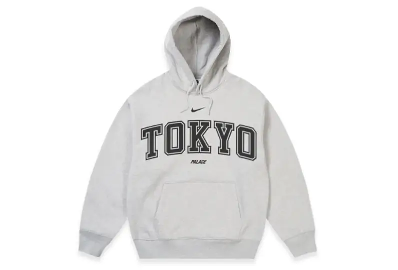 Front view of a heather gray Nike x Palace Tokyo hoodie featuring oversized varsity-style "TOKYO" lettering, a Nike Swoosh above the logo, Palace branding beneath, and a spacious kangaroo pocket