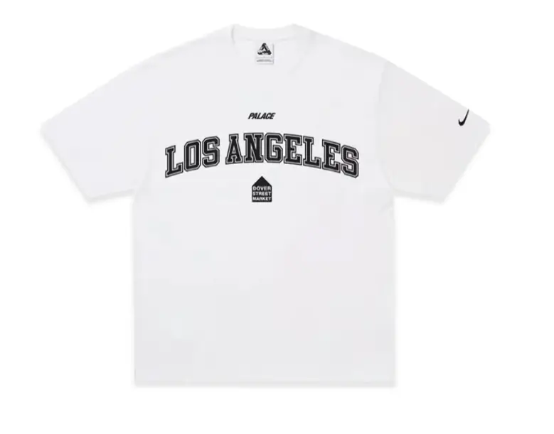 White Nike x Palace Los Angeles T-shirt with large collegiate "LOS ANGELES" lettering across the chest, Palace branding above a Dover Street Market logo, and a black Nike Swoosh on the right sleeve