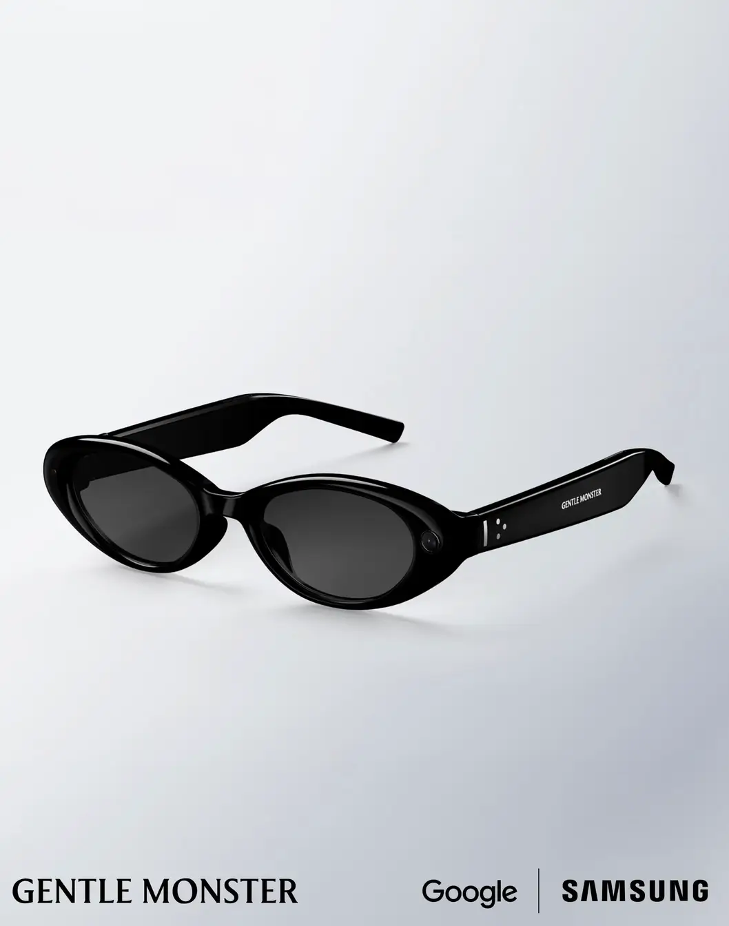 Black Gentle Monster smart glasses created with Samsung and Google, featuring glossy oval acetate frames, dark tinted lenses, integrated AI hardware, and discreet side-mounted sensors displayed against a clean white studio background.