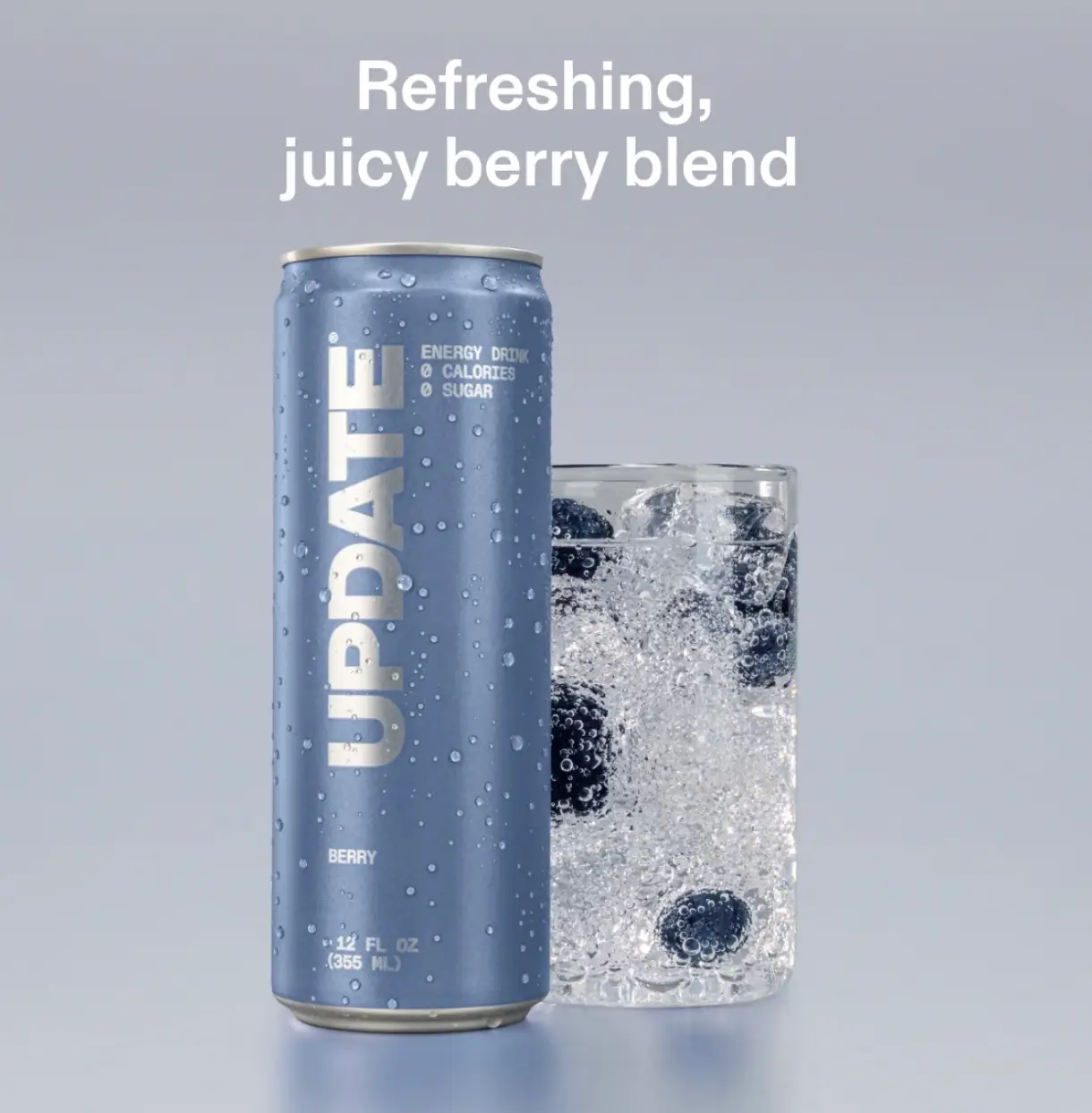 A blue UPTIME Berry energy drink can covered in condensation stands beside a clear glass filled with sparkling ice and dark berries against a light gray background.