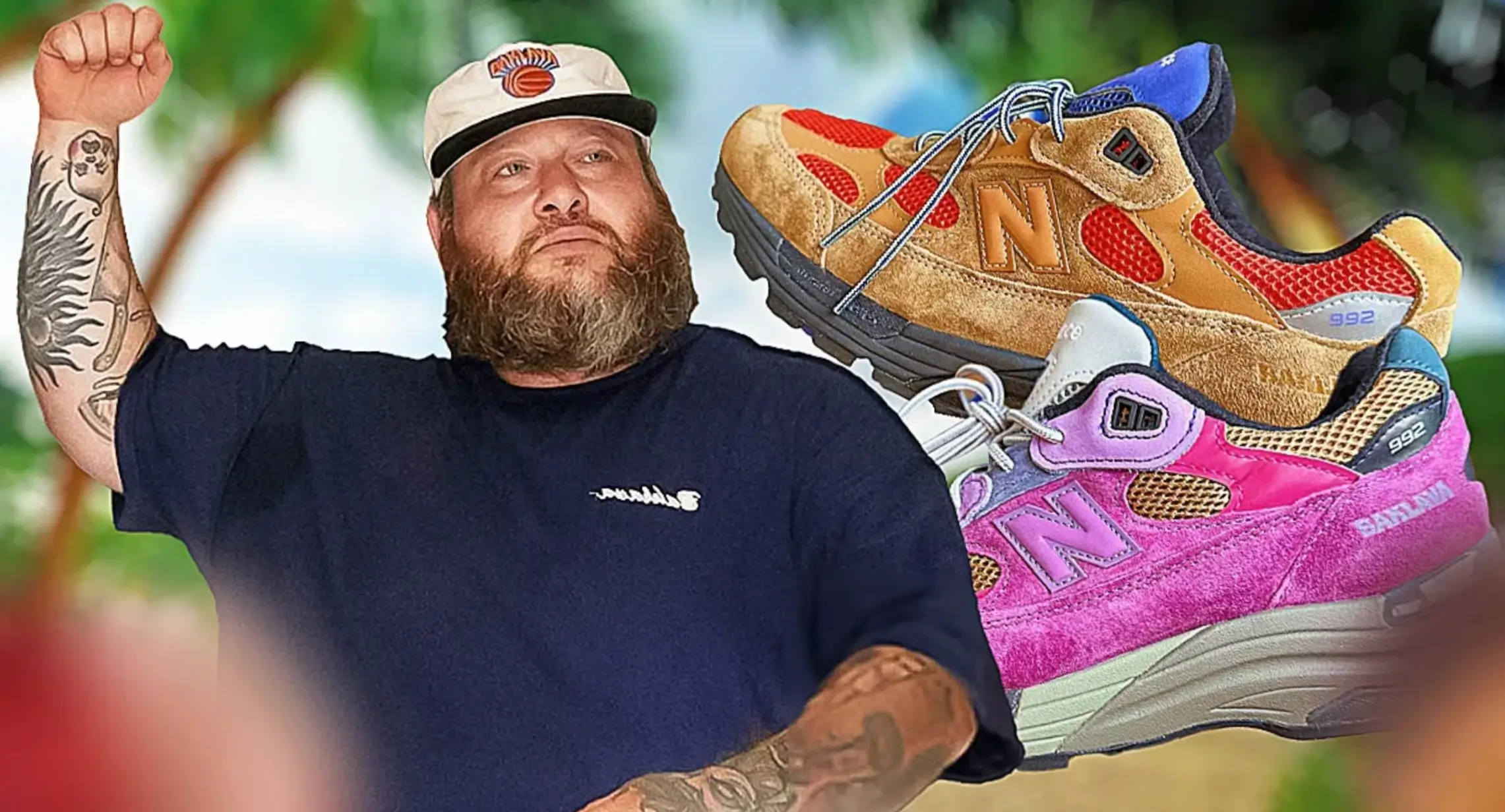Action Bronson raises a clenched fist while wearing a navy T-shirt and a cream New York Knicks cap. Two of his New Balance 992 collaborations are composited beside him: one in tan suede with orange mesh, blue accents, and a black midsole, and another in bright pink suede with lavender, cream, and black details. The blurred tropical-style background gives the collage a bold promotional look.