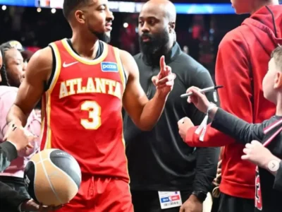 Atlanta Hawks player greets young fans courtside after a game as they hold out basketballs and markers for autographs