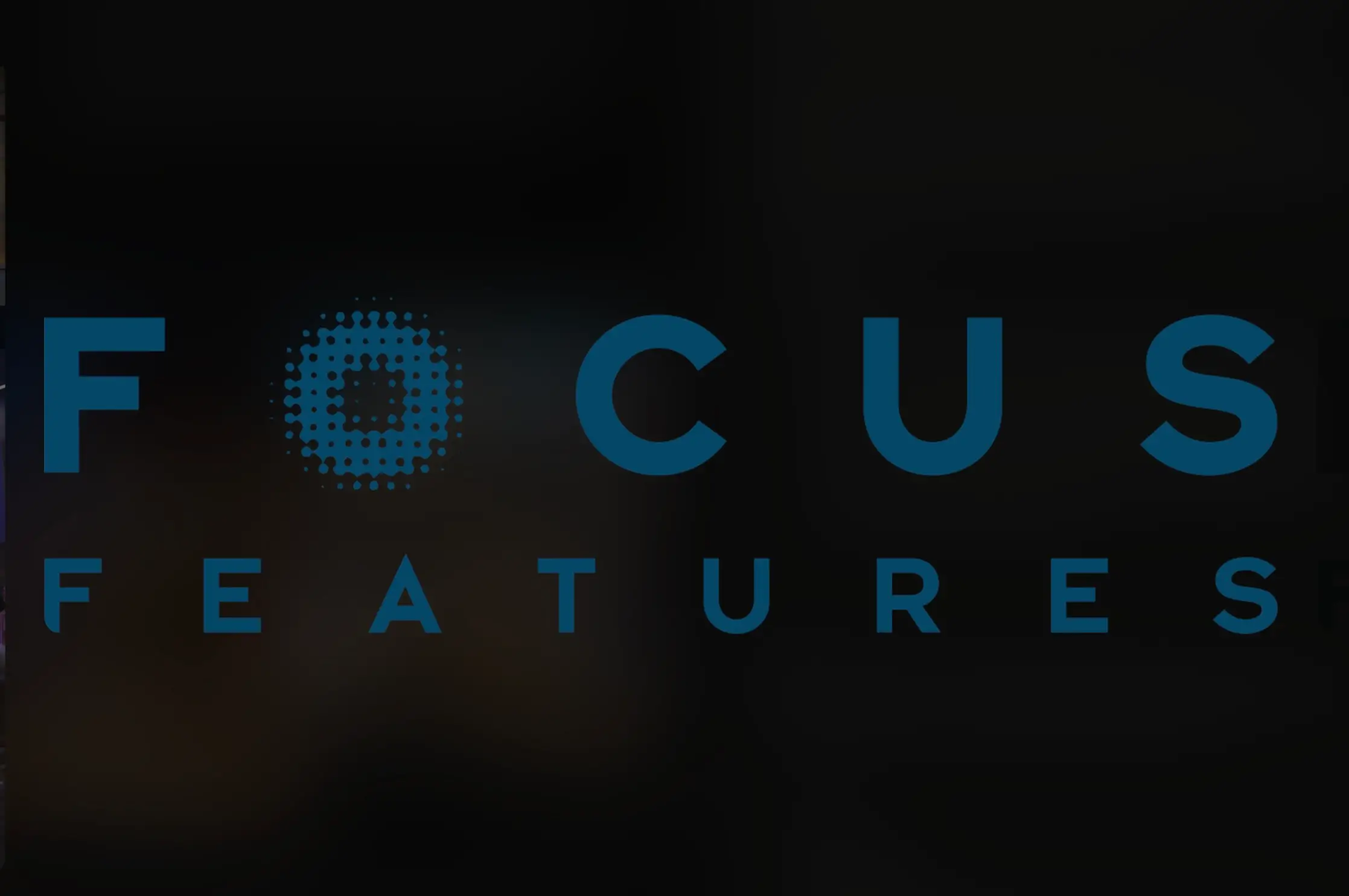 Focus Features logo displayed in blue against a dark black background, with the company's stylized dotted 'O' mark and minimalist typography centered across the frame.