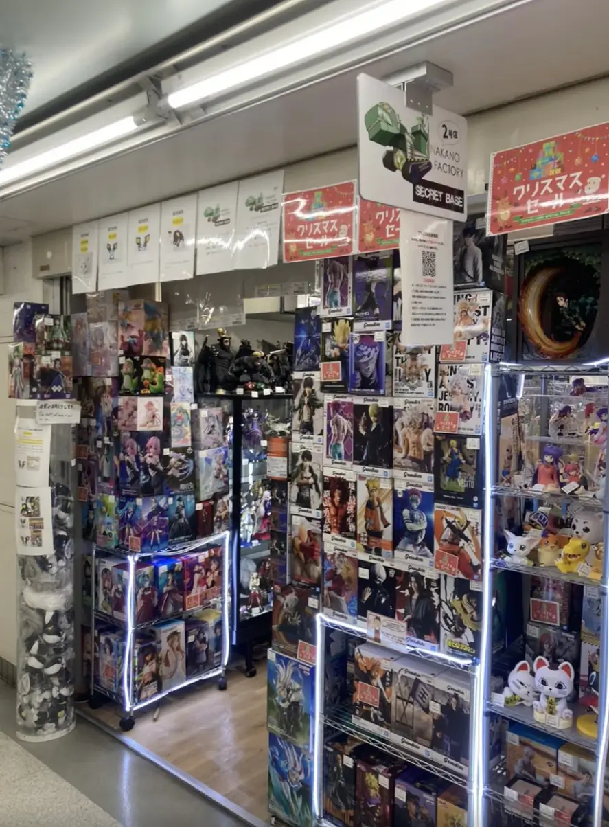 SECRET BASE Nakano Factory store in Japan filled with anime figures, collectible statues, designer toys, and character merchandise displayed on illuminated shelves and stacked boxes.