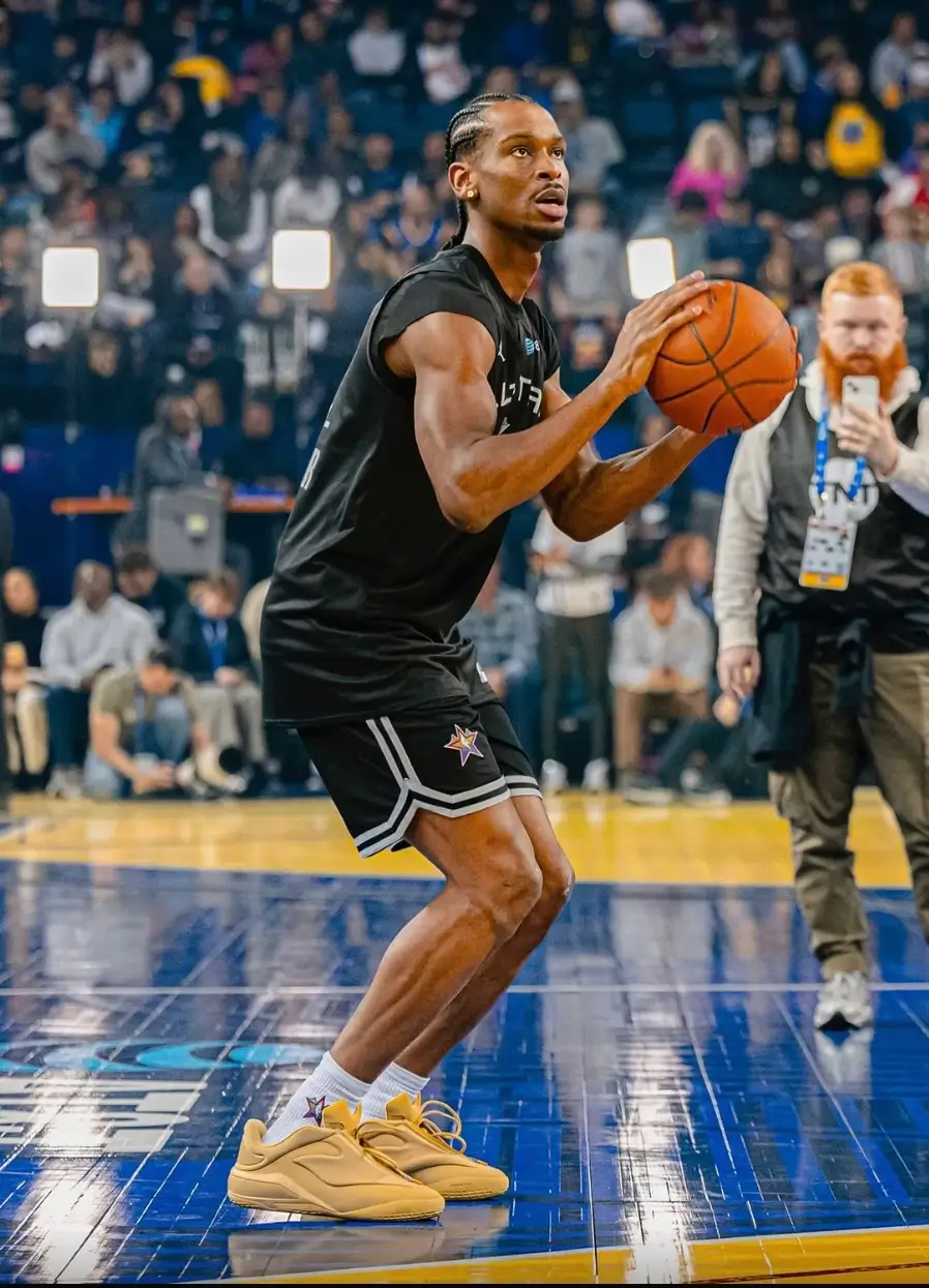 Shai Gilgeous-Alexander warming up before an NBA game while wearing an unreleased wheat-colored Converse SHAI basketball shoe with black All-Star practice uniform.