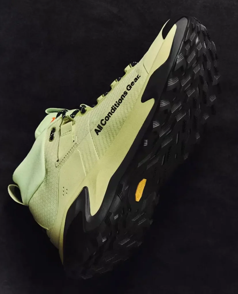 Nike ACG Zegama Hike trail shoe in pale volt with a Vibram outsole, rugged lug pattern, and "All Conditions Gear" branding shown from the outsole angle