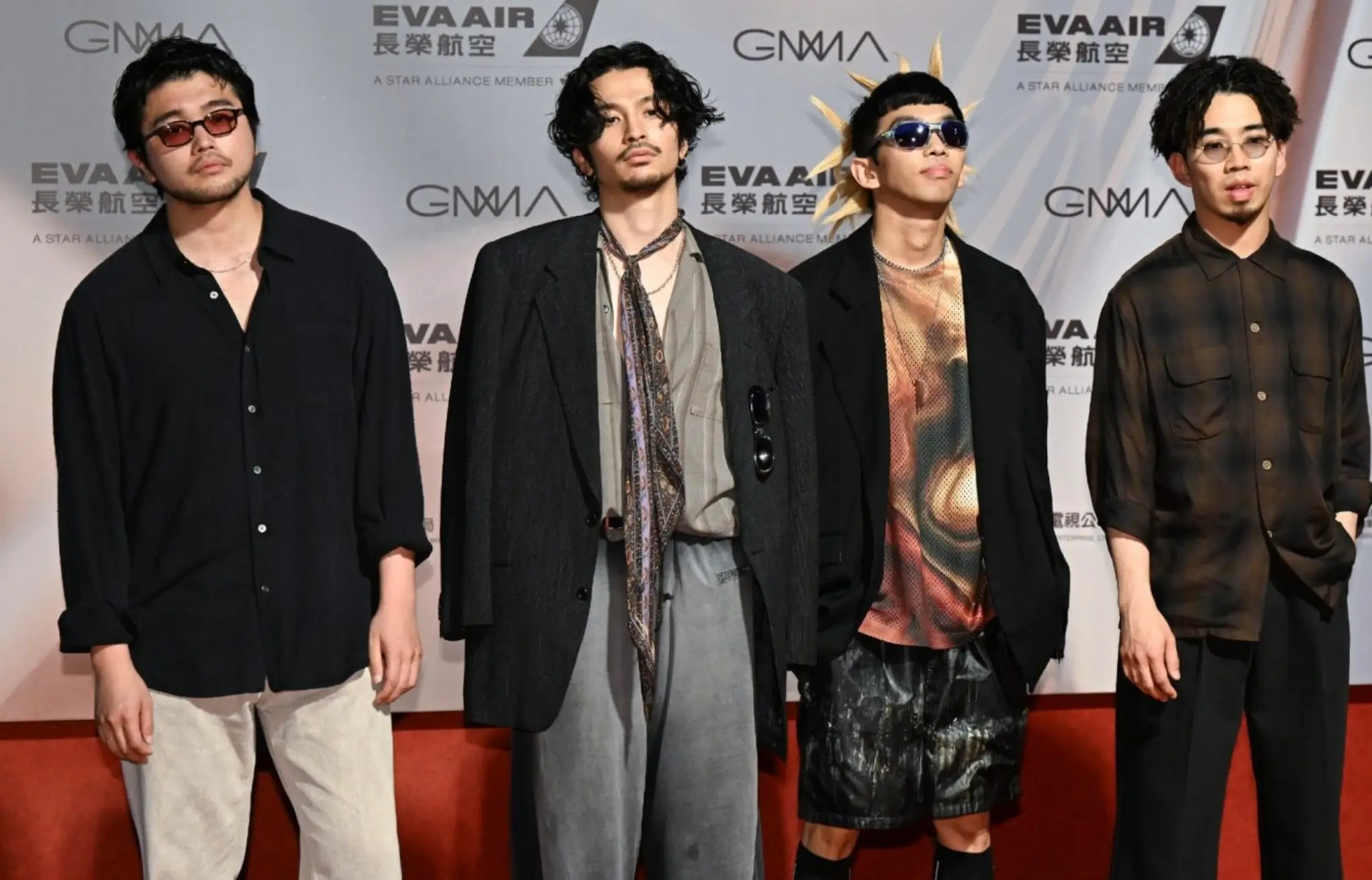 Four-member Japanese band posing on the red carpet in contemporary designer outfits and sunglasses at the GMA Gala, with EVA Air sponsor backdrop.