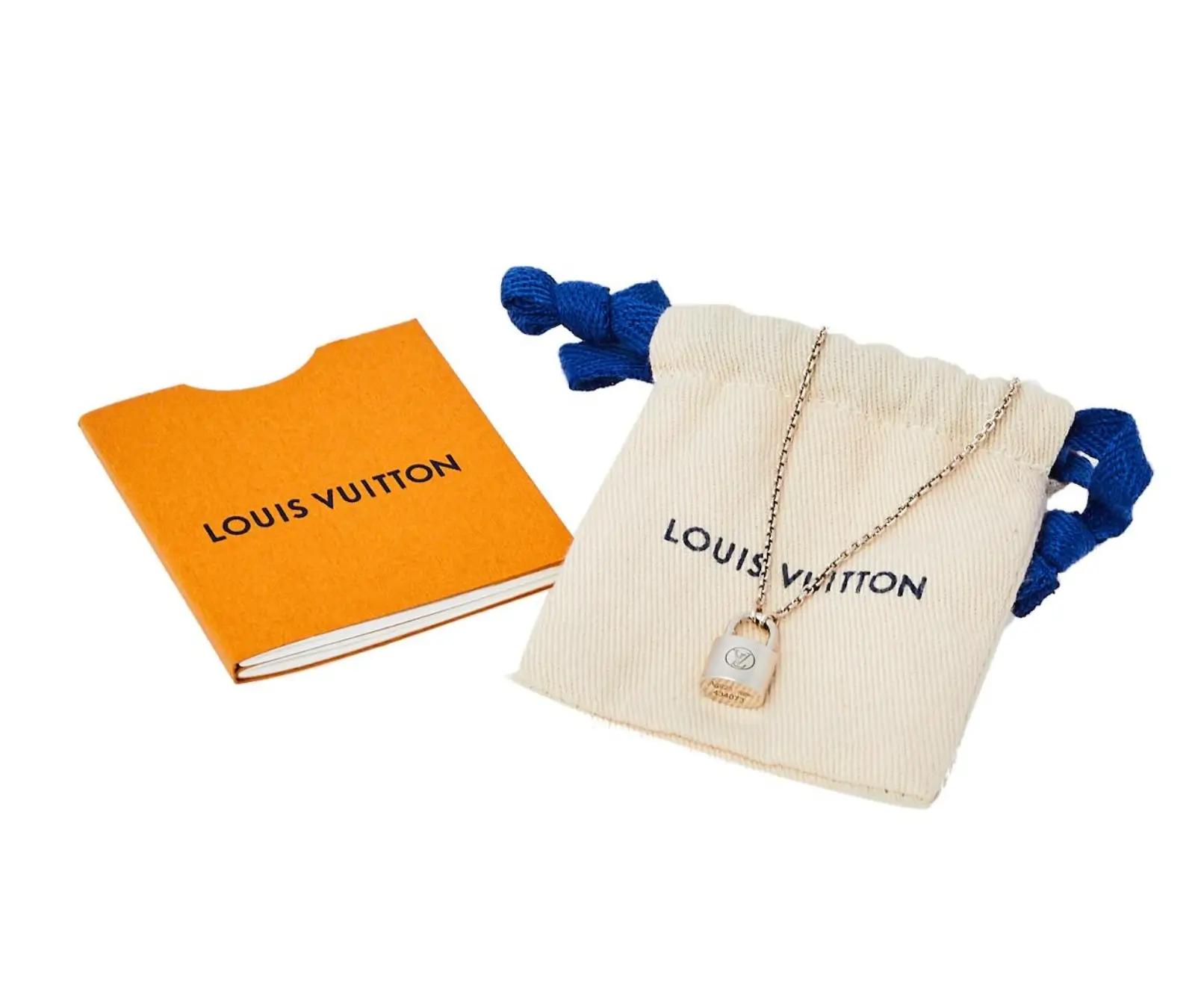 A Louis Vuitton padlock pendant necklace displayed on a fine chain beside the House's signature cream drawstring pouch with blue cords and an orange Louis Vuitton booklet, highlighting the brand's iconic packaging and jewelry presentation.