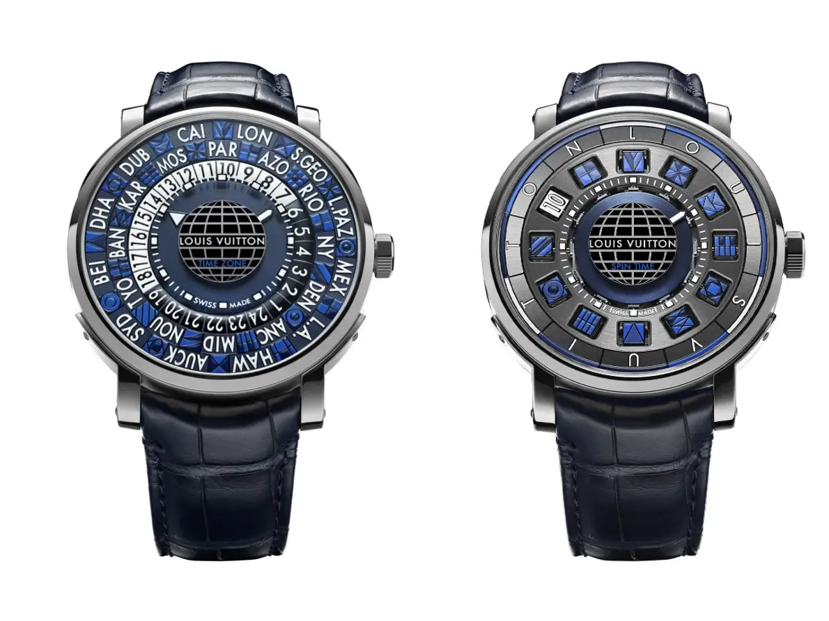 Two Louis Vuitton Tambour watches displayed side by side, featuring intricate blue and gray dials with rotating world time and spin time complications, polished metal cases, and matching navy alligator leather straps.