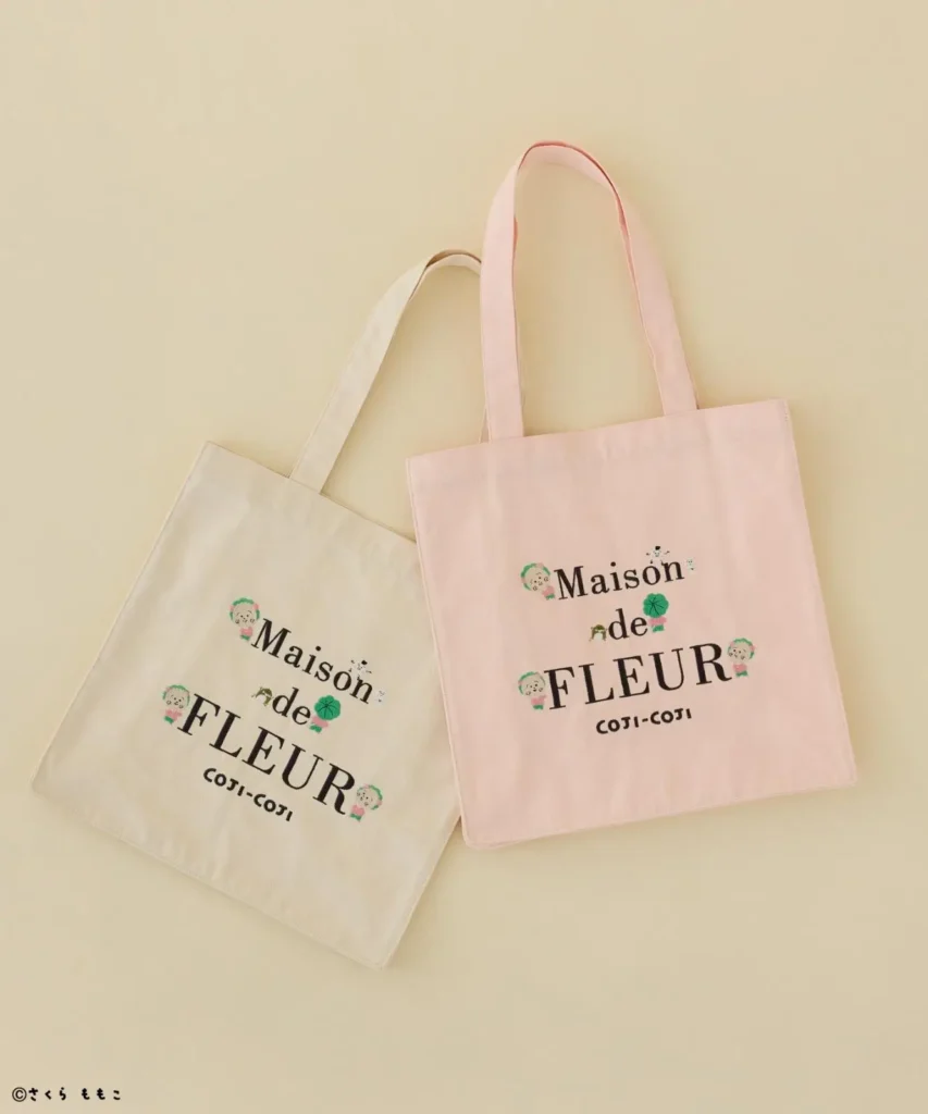Two canvas tote bags, one cream and one pink, featuring Maison de FLEUR and Kojikoji character designs