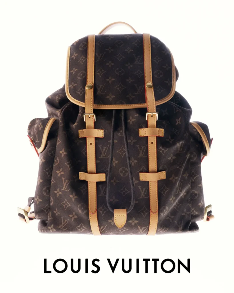 Louis Vuitton monogram backpack with natural leather straps, buckle closures, flap top, and multiple exterior pockets presented front-facing on a white background